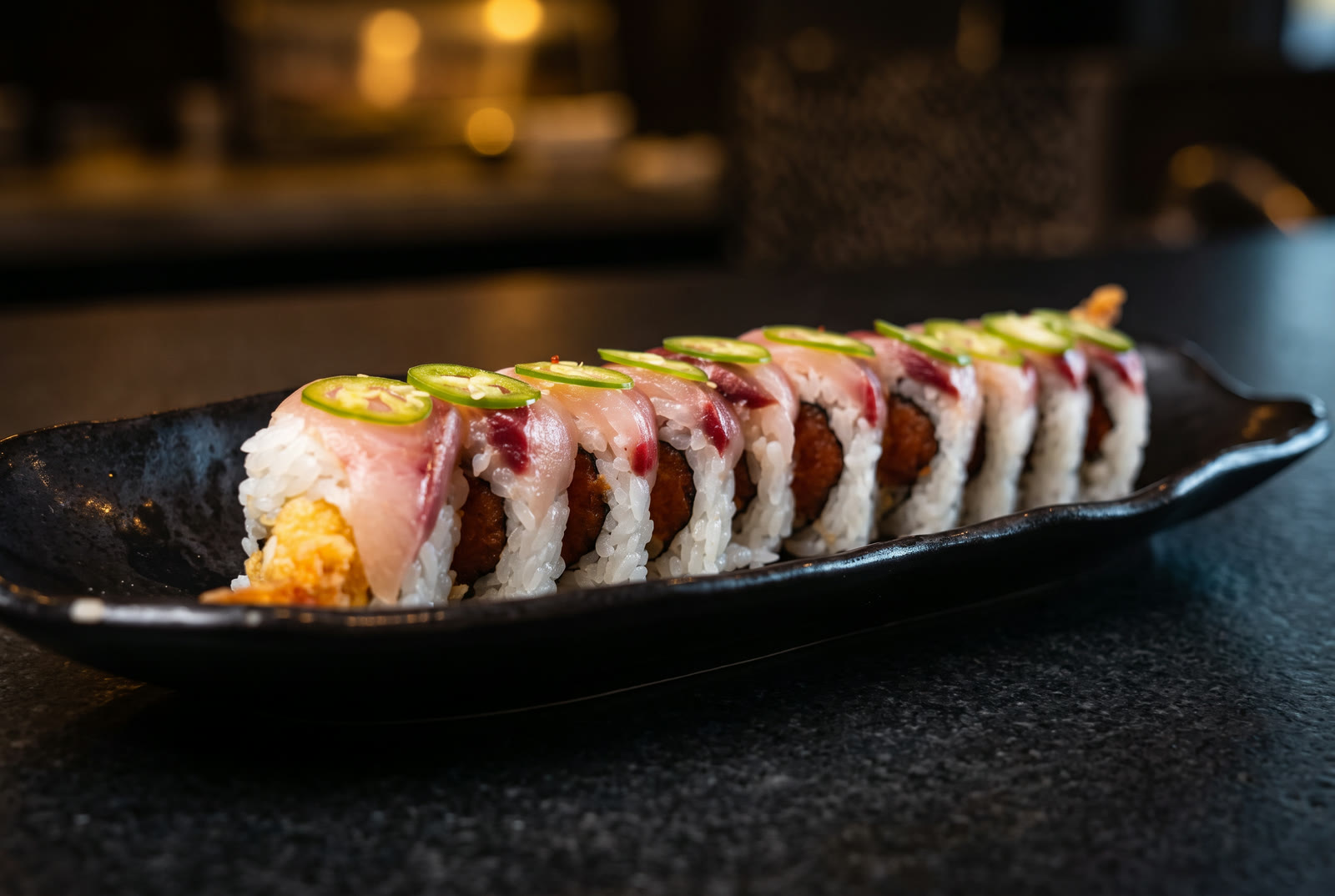 Texas roll — shrimp tempura and spicy tuna topped with yellowtail and Serrano peppers
